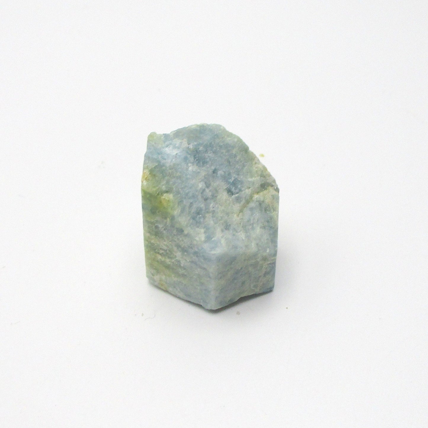 A rough Aquamarine crystal with a translucent blue color on a white background.