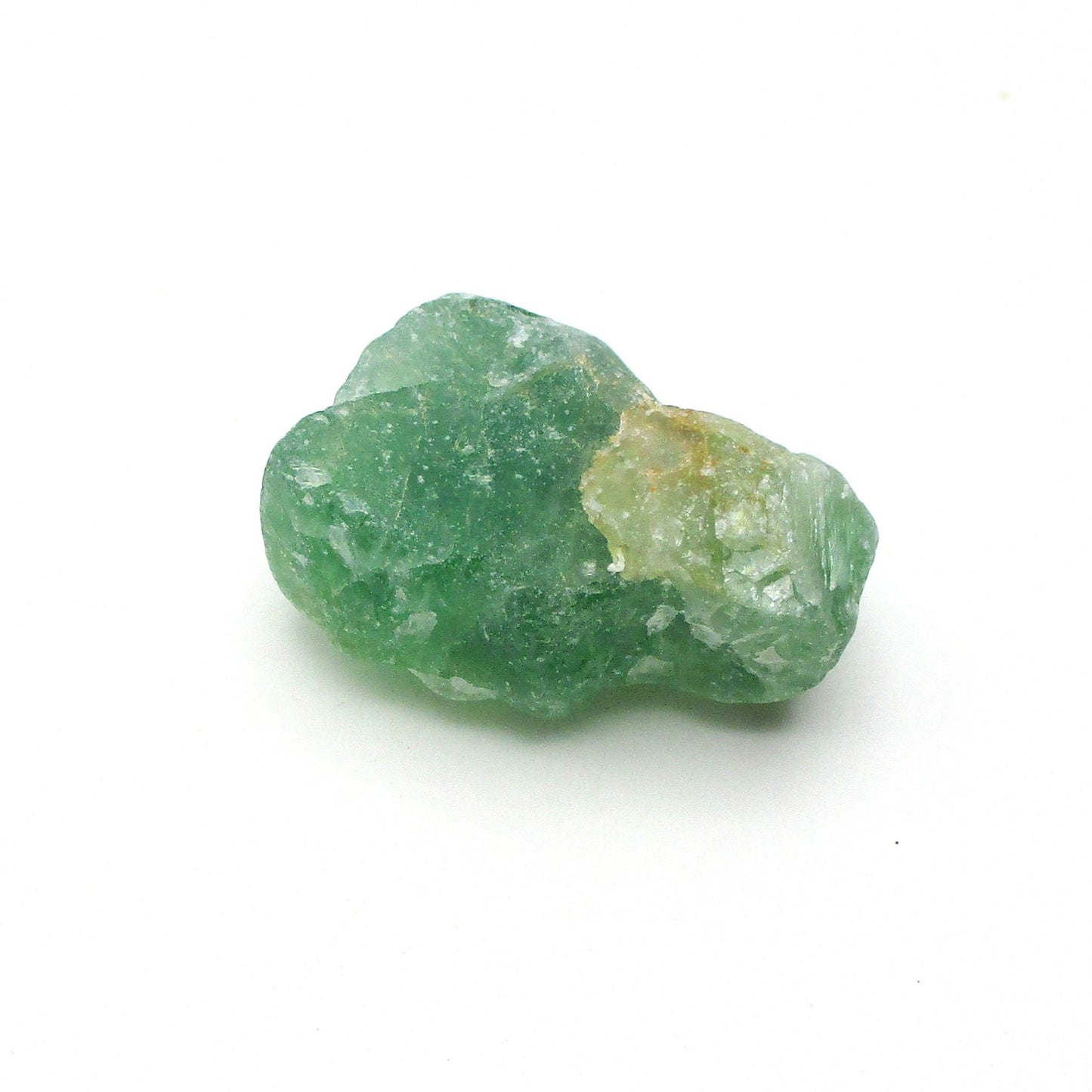 A green fluorite crystal with natural imperfections on a white background.