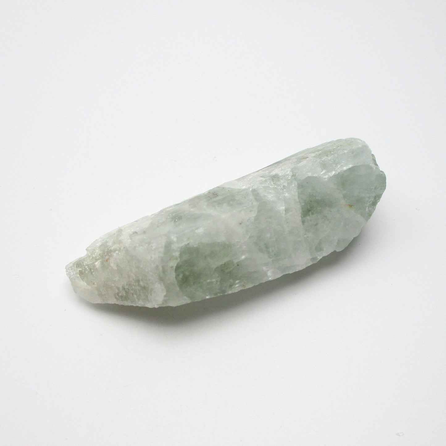 A rough Aquamarine crystal with a pale green color, elongated in shape, placed on a white background.