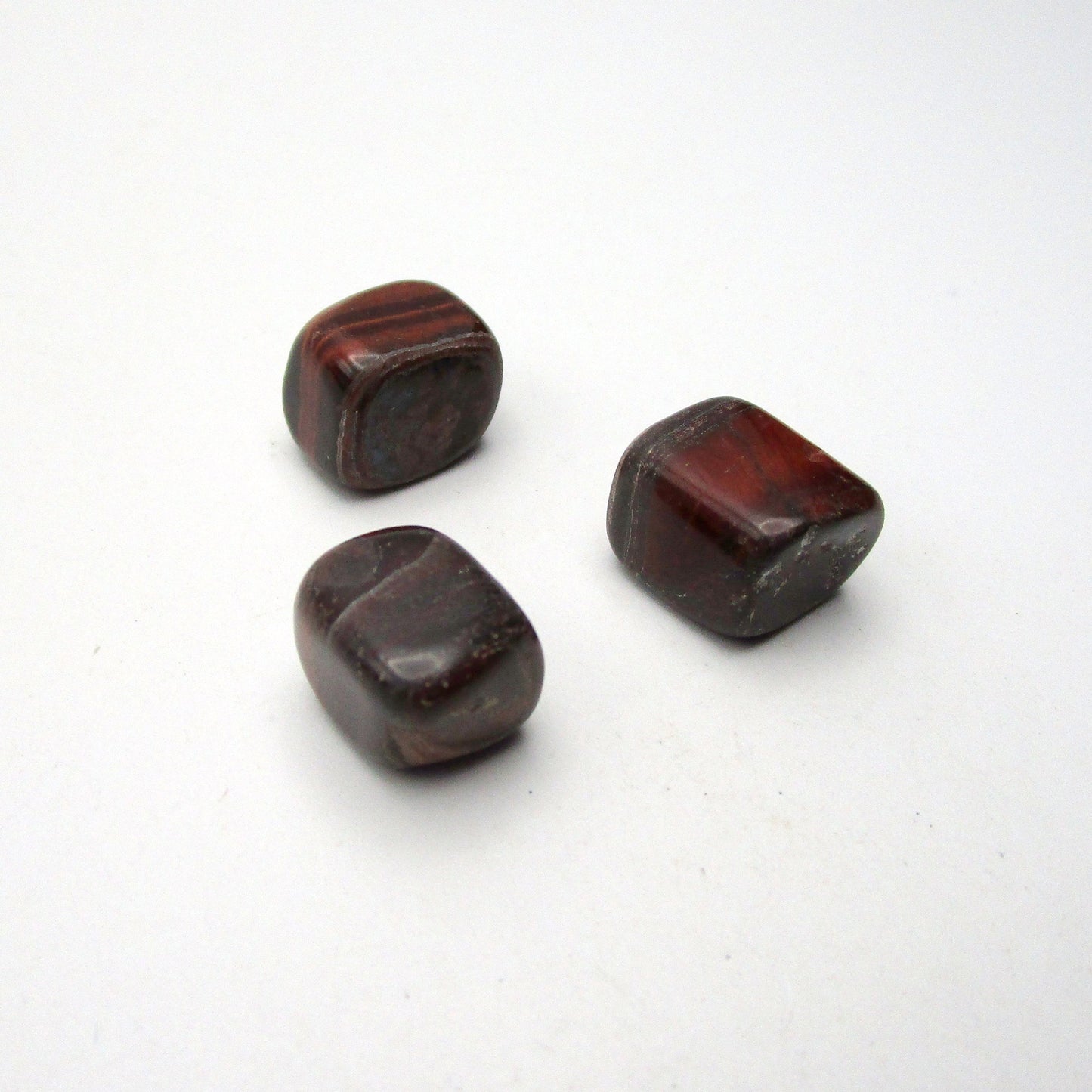 Set of three tumbled red tigers eye on white background
