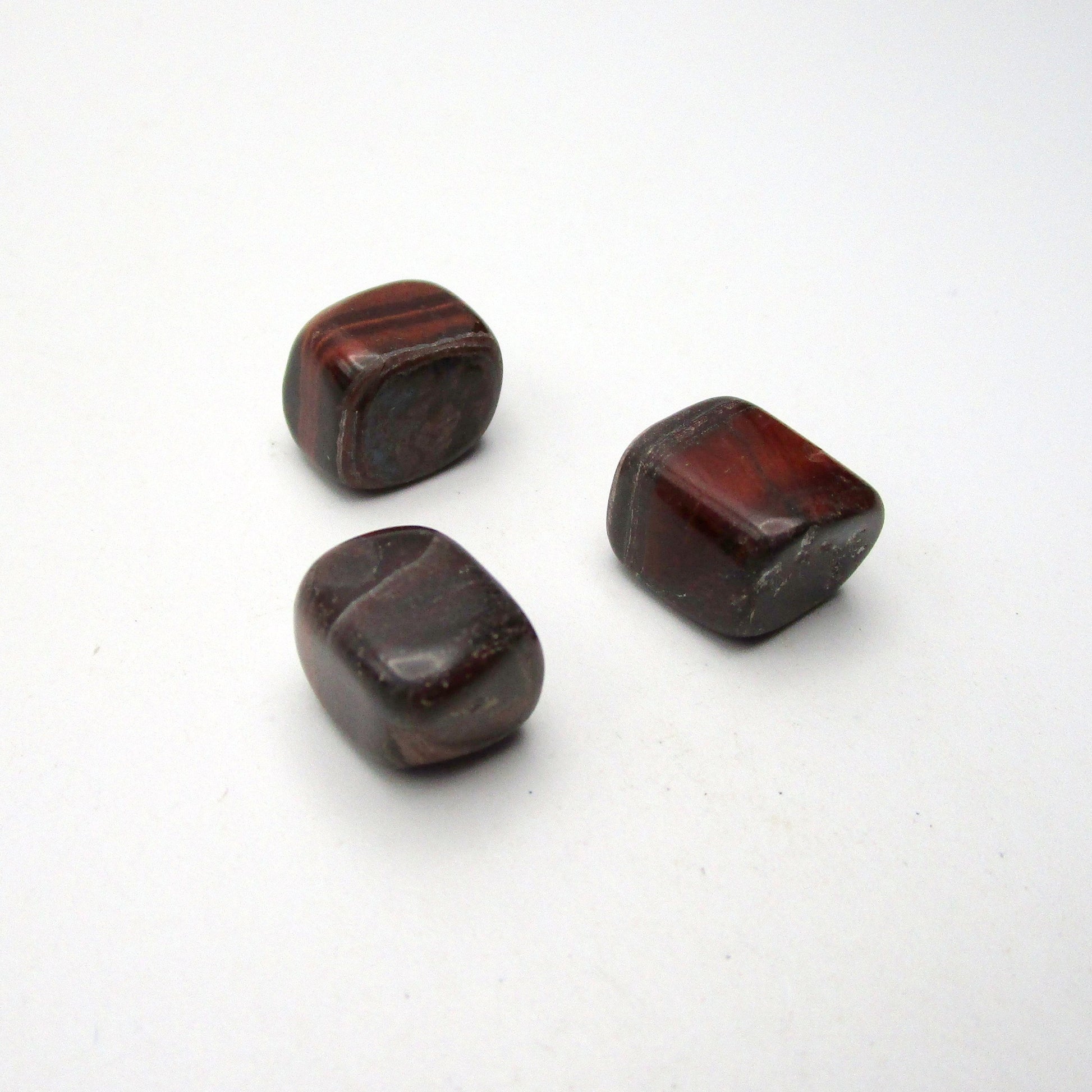 Set of three tumbled red tigers eye on white background