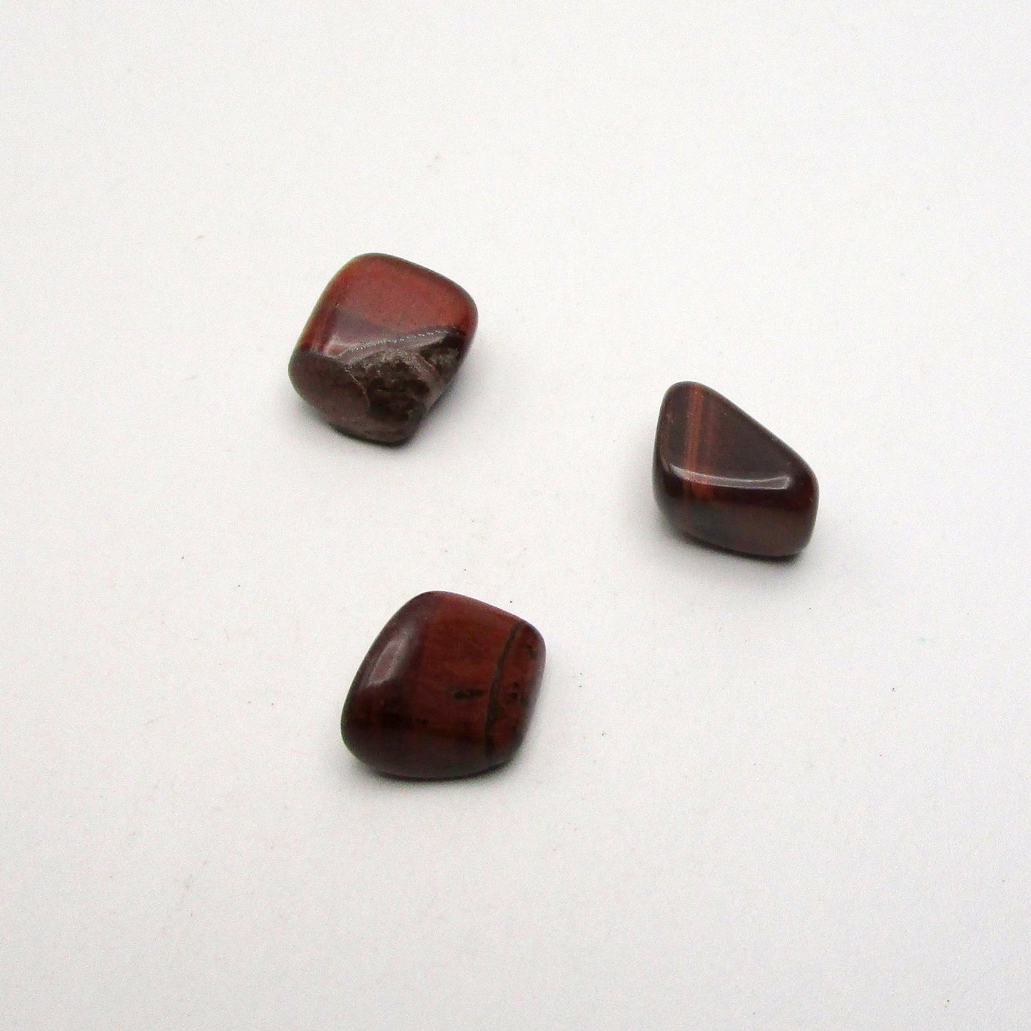 Set of three tumbled red tigers eye on white background
