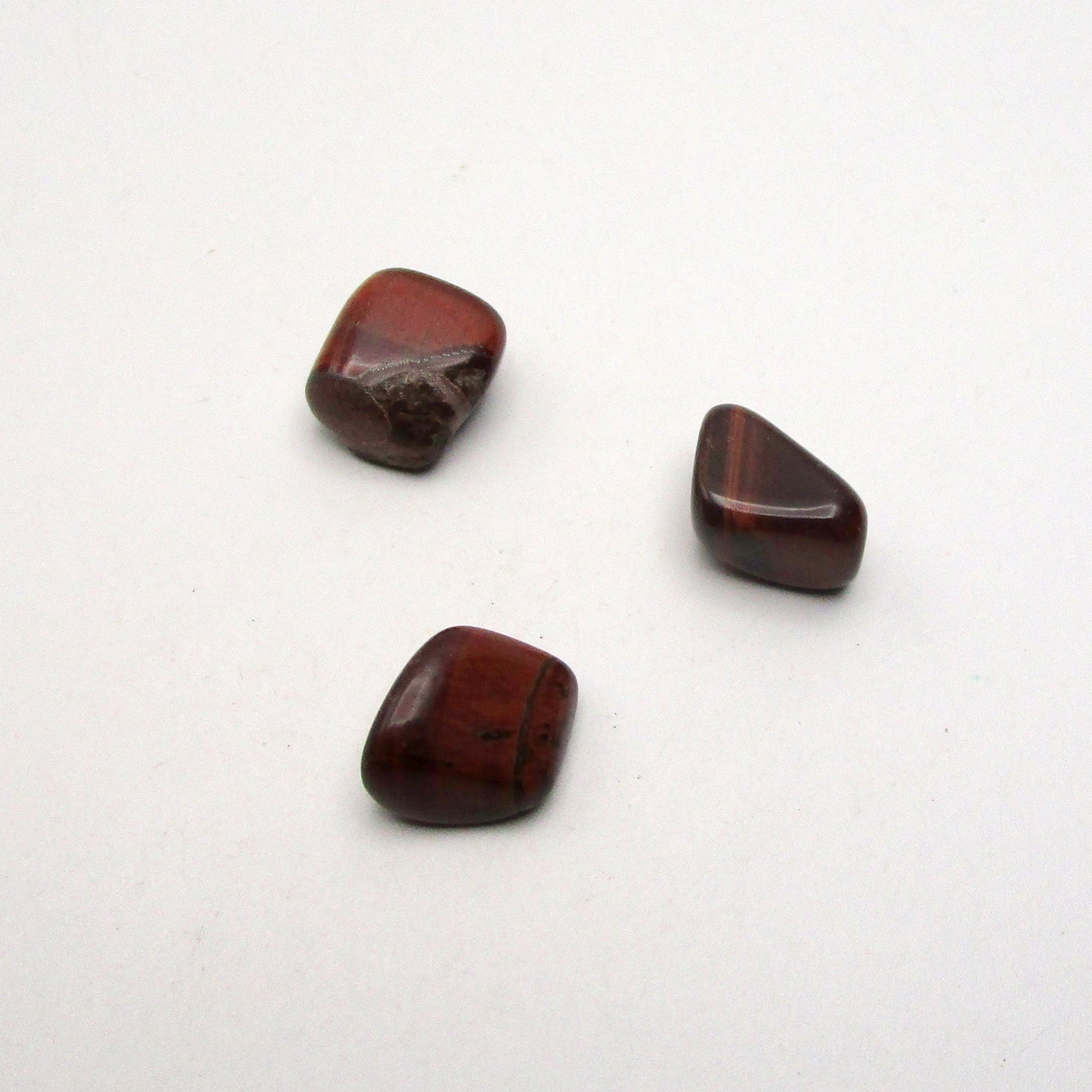 Set of three tumbled red tigers eye on white background