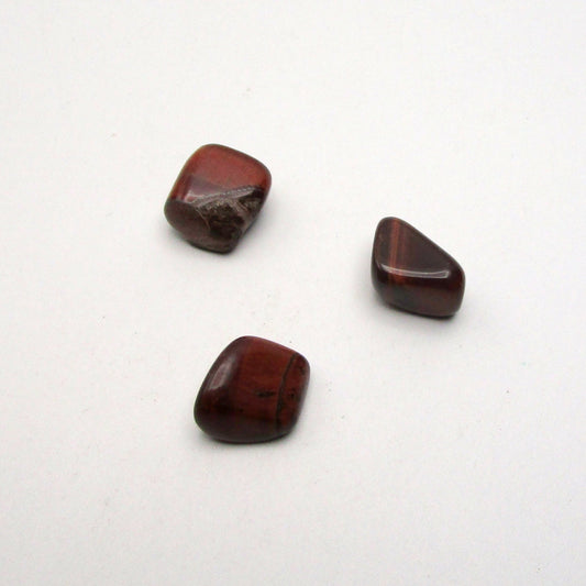 Set of three tumbled red tigers eye on white background