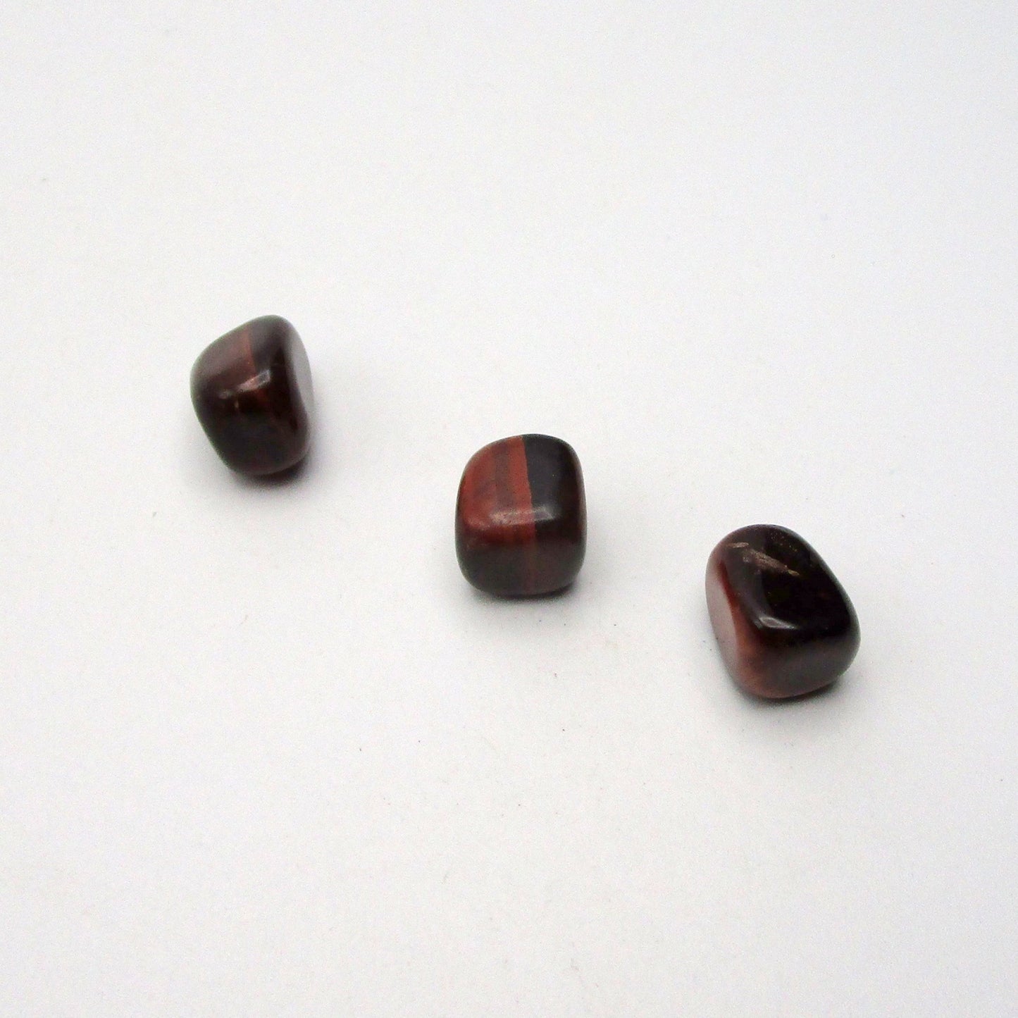 Set of three tumbled red tigers eye on white background