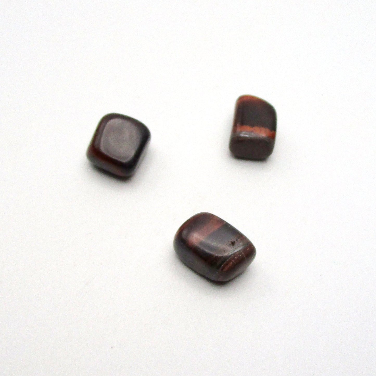 Set of three tumbled red tigers eye on white background