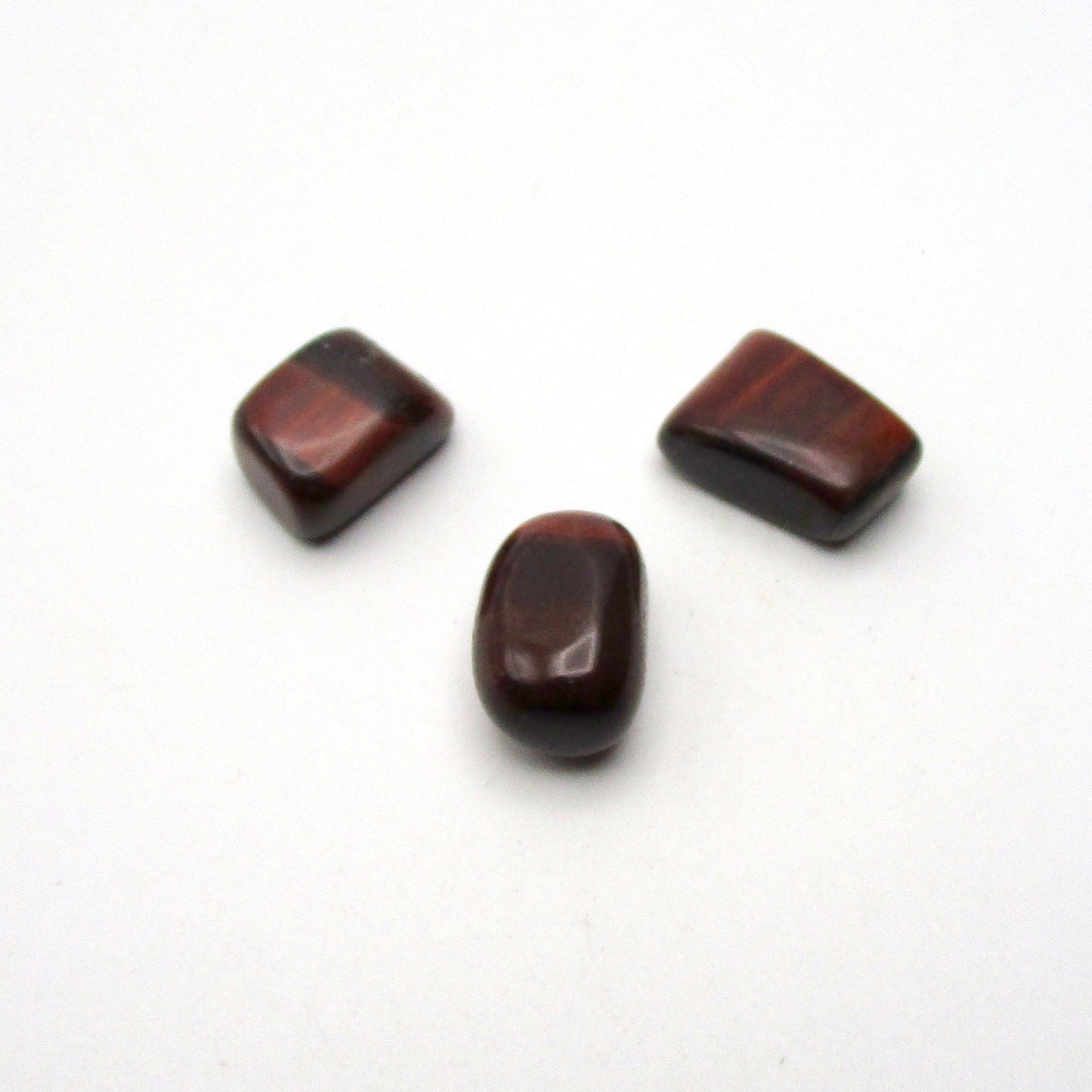 Set of three tumbled red tigers eye on white background