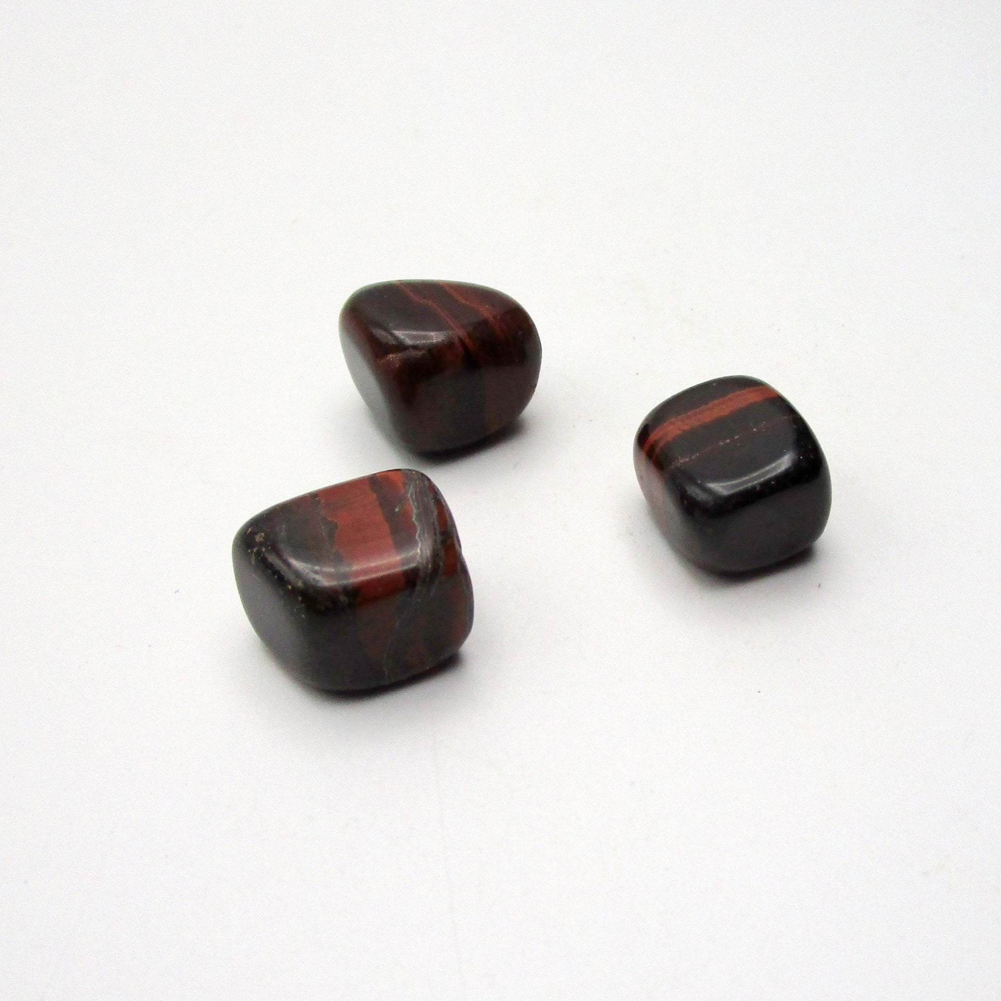 Set of three tumbled red tigers eye on white background