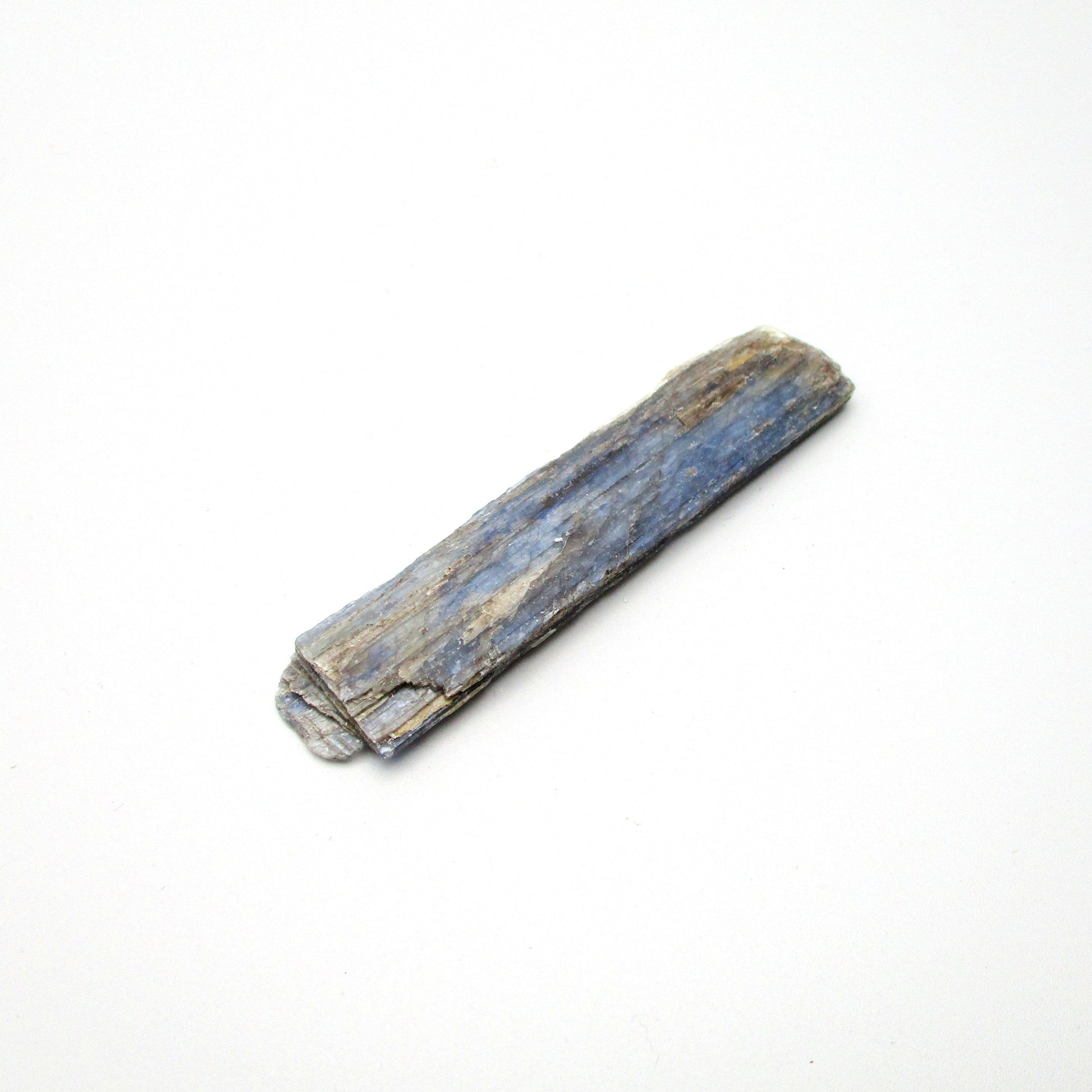 A raw Brazilian blue kyanite crystal displayed on a white background
