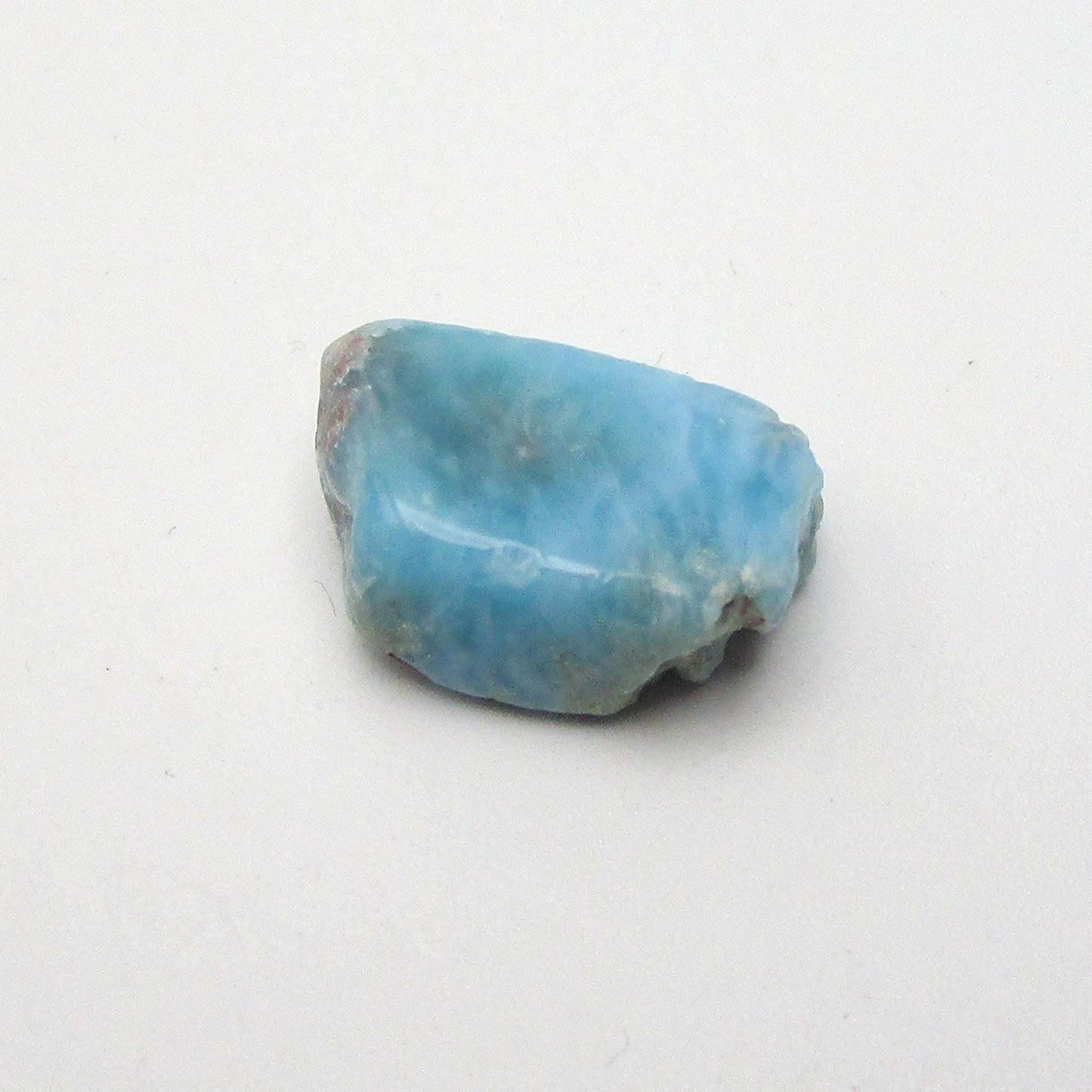 A polished piece of blue Larimar crystal on a white background