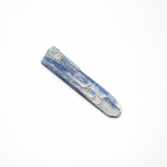 A rough, unpolished piece of blue kyanite crystal with natural imperfections on a white background