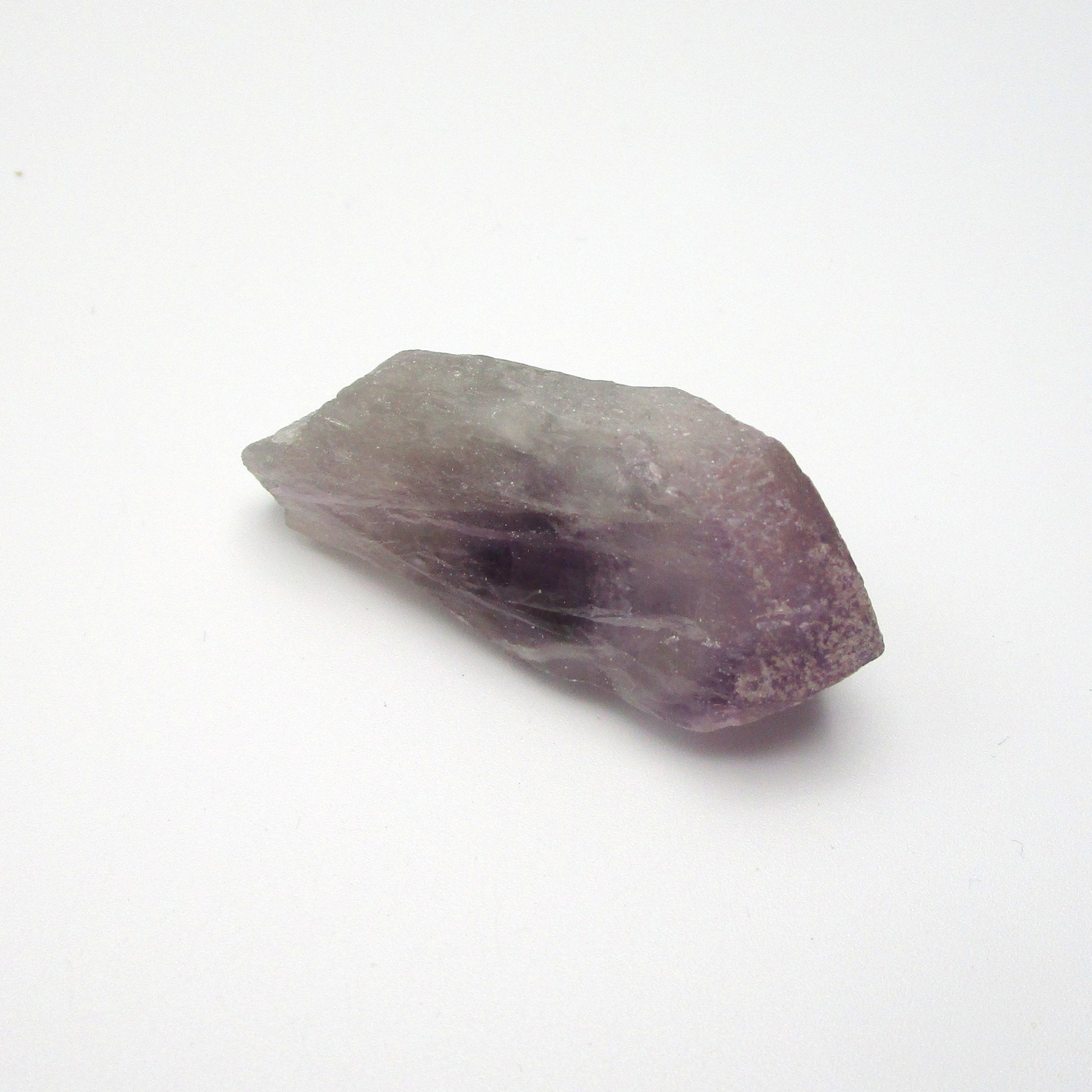 A Brazilian Amethyst Point crystal with a range of purple colors against a white background.
