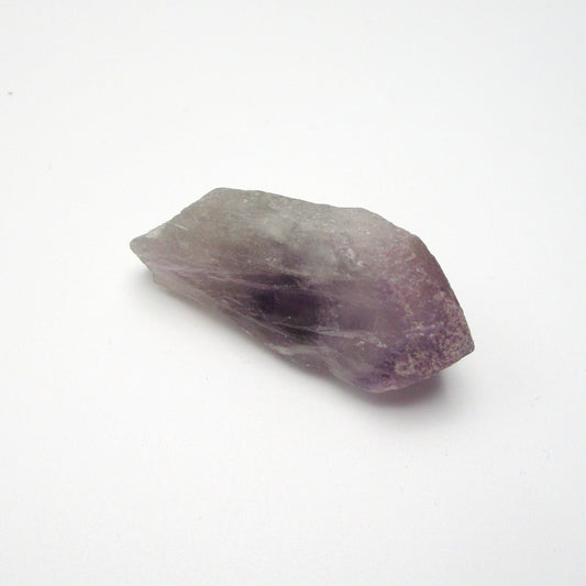A Brazilian Amethyst Point crystal with a range of purple colors against a white background.