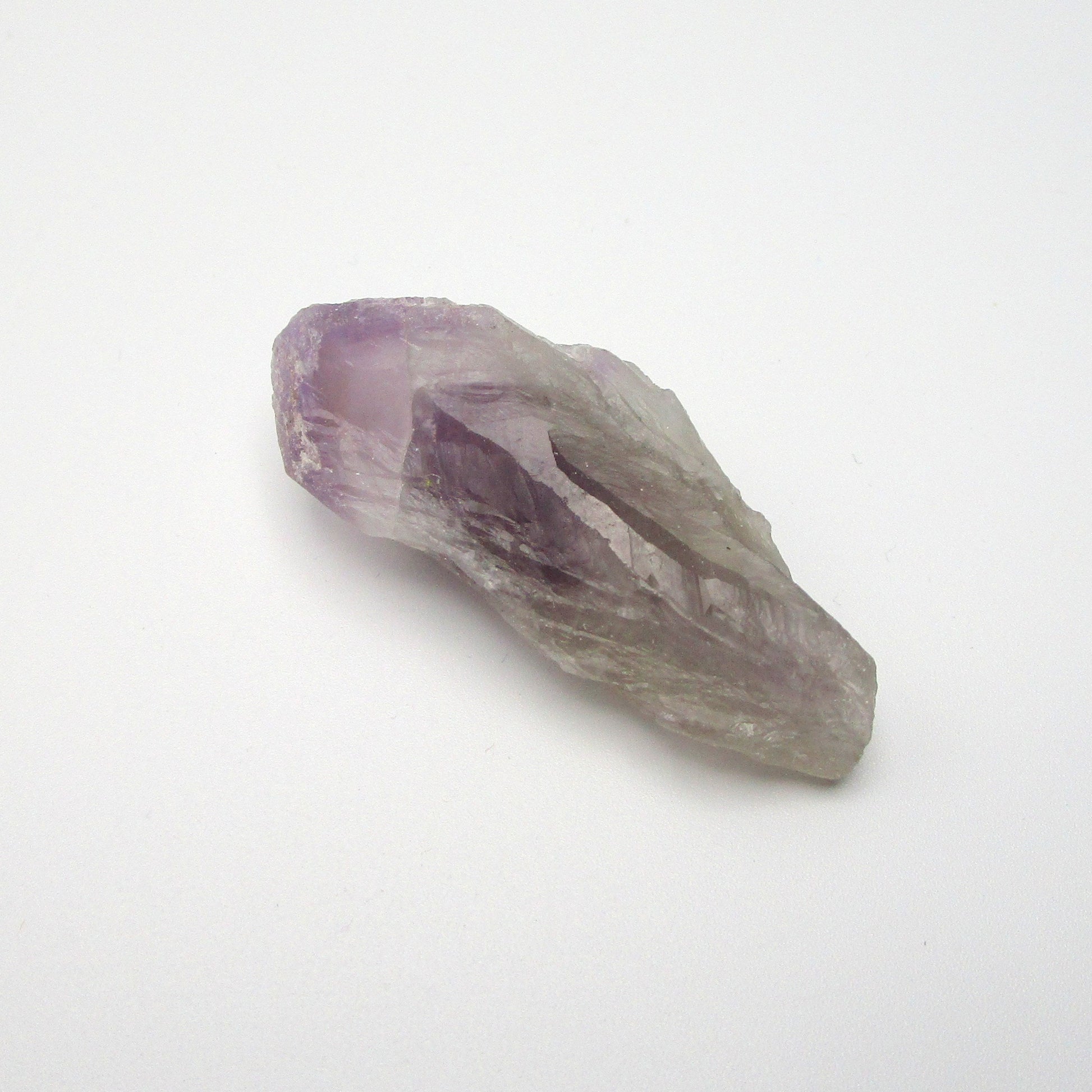 A Brazilian Amethyst Point crystal with a range of purple colors against a white background.