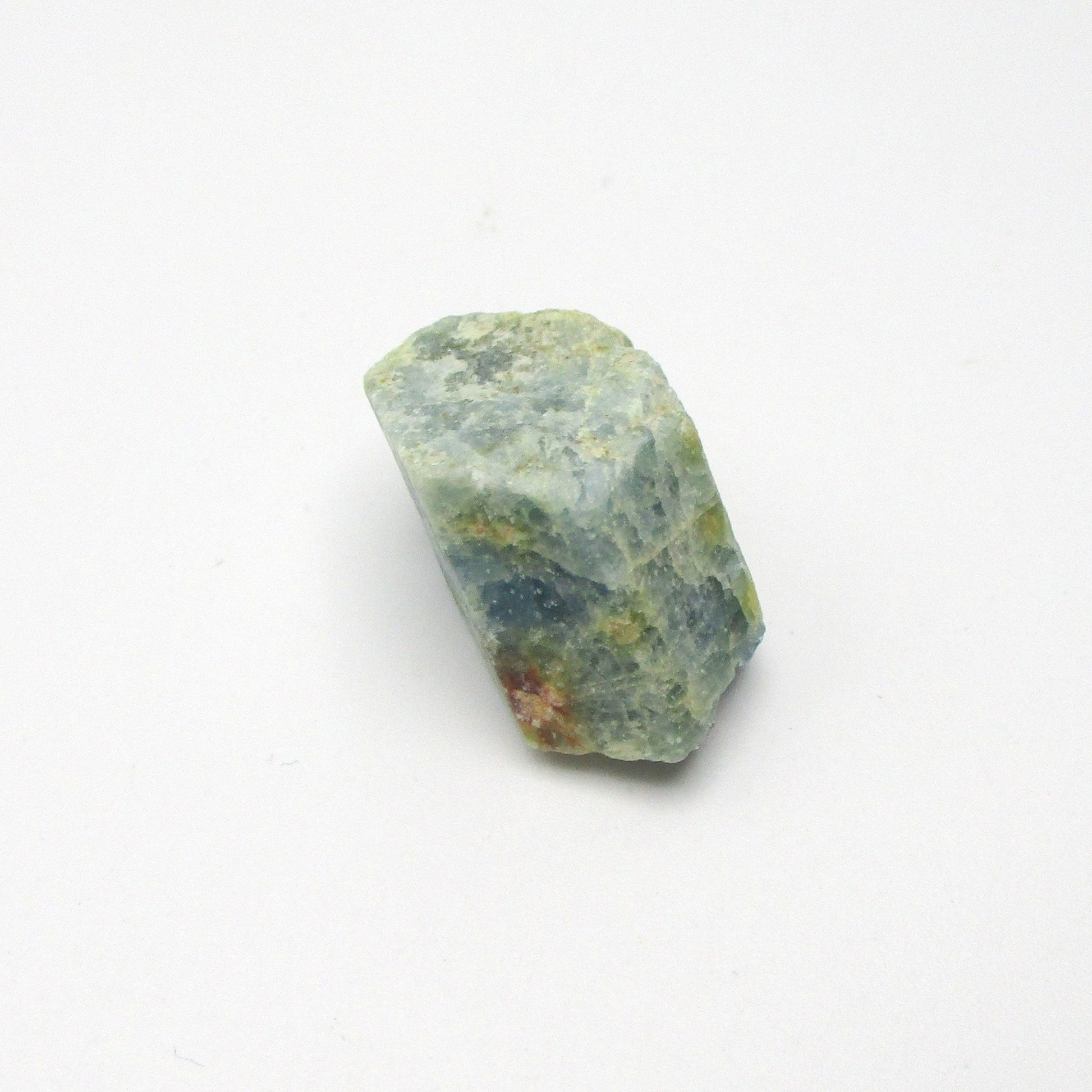 A rough-cut Aquamarine gemstone with a pale blue color and hints of green, displaying natural crystal textures and minor imperfections.