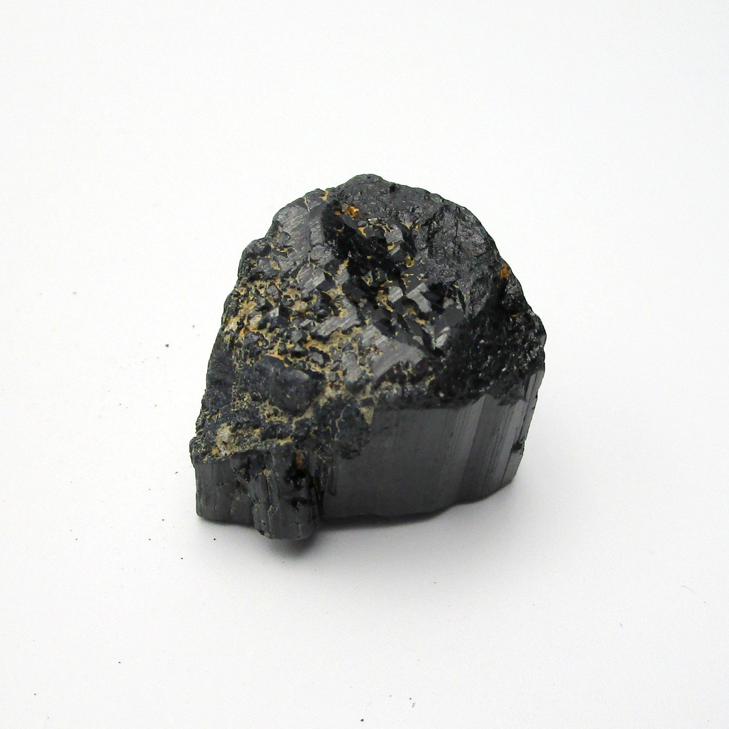 A rough, black tourmaline crystal with a metallic sheen, approximately 1 inch in size, displayed on a white background.