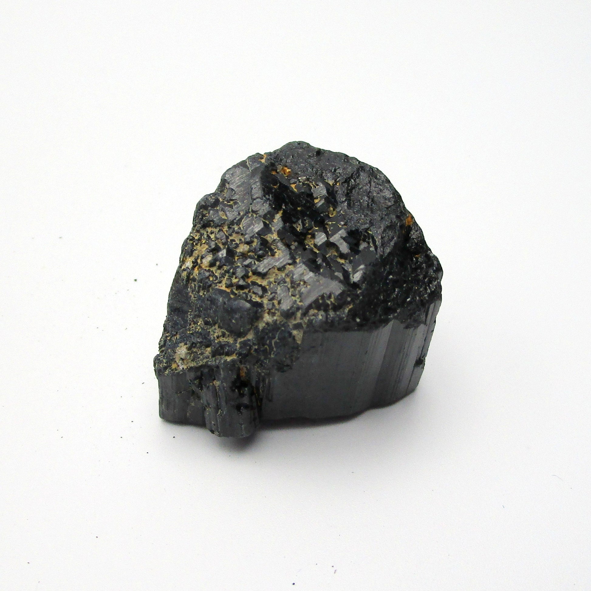 A rough, black tourmaline crystal with a metallic sheen, approximately 1 inch in size, displayed on a white background.