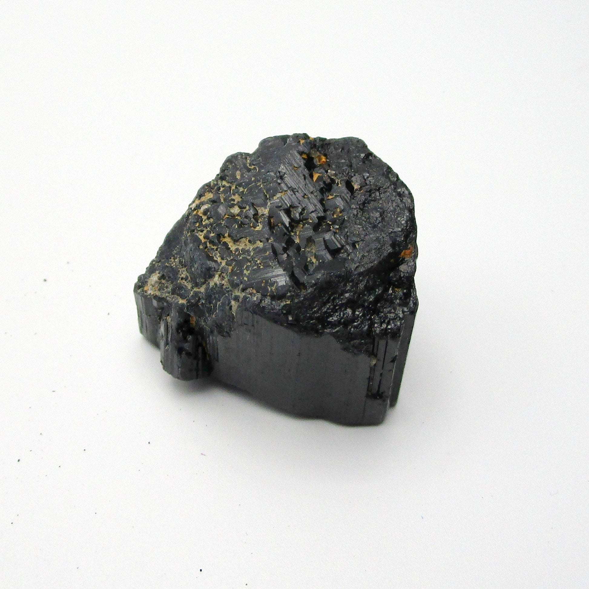 A rough, black crystal piece of Black Tourmaline against a white background.