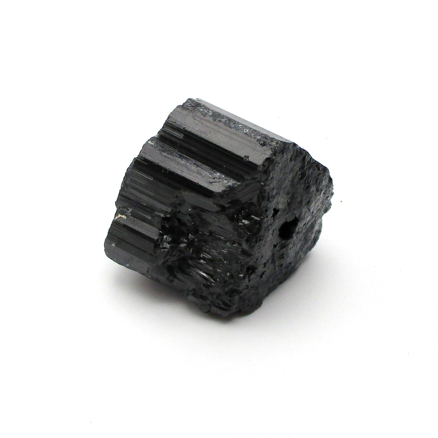 A rough, black tourmaline crystal with a metallic sheen, approximately 1 inch in size, displayed on a white background.