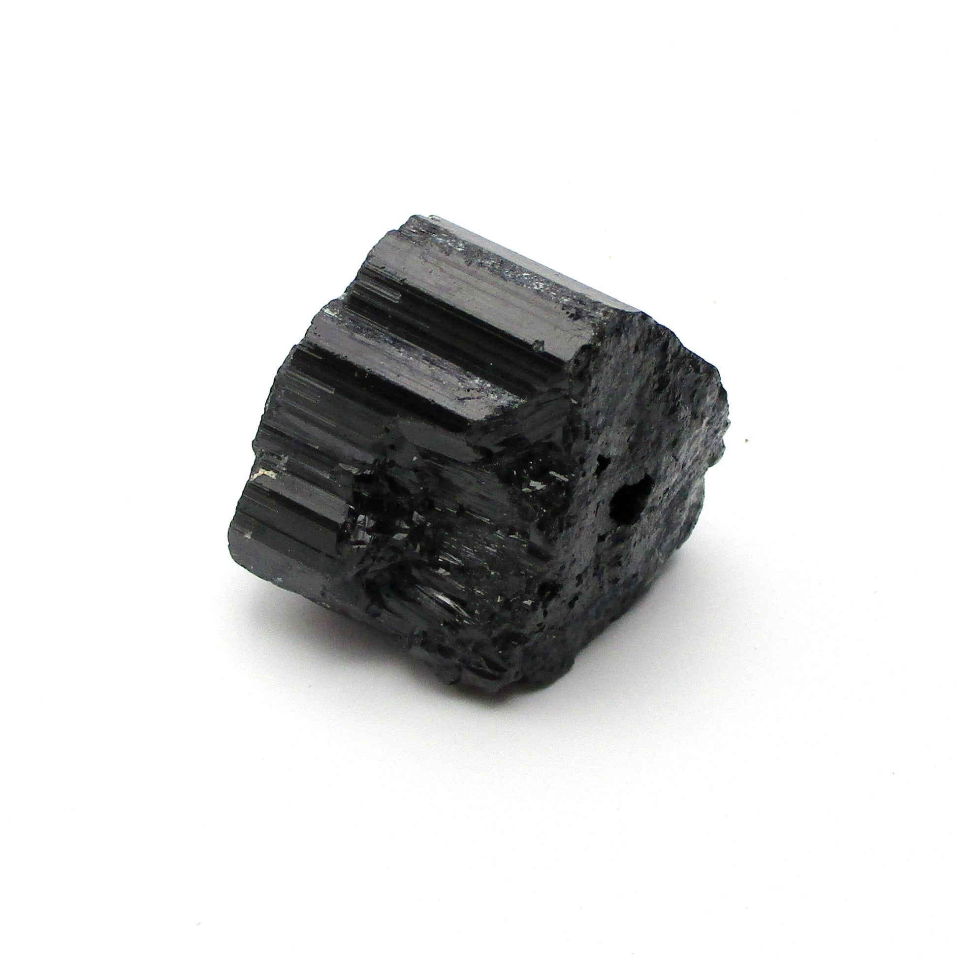 A rough, black tourmaline crystal with a metallic sheen, approximately 1 inch in size, displayed on a white background.