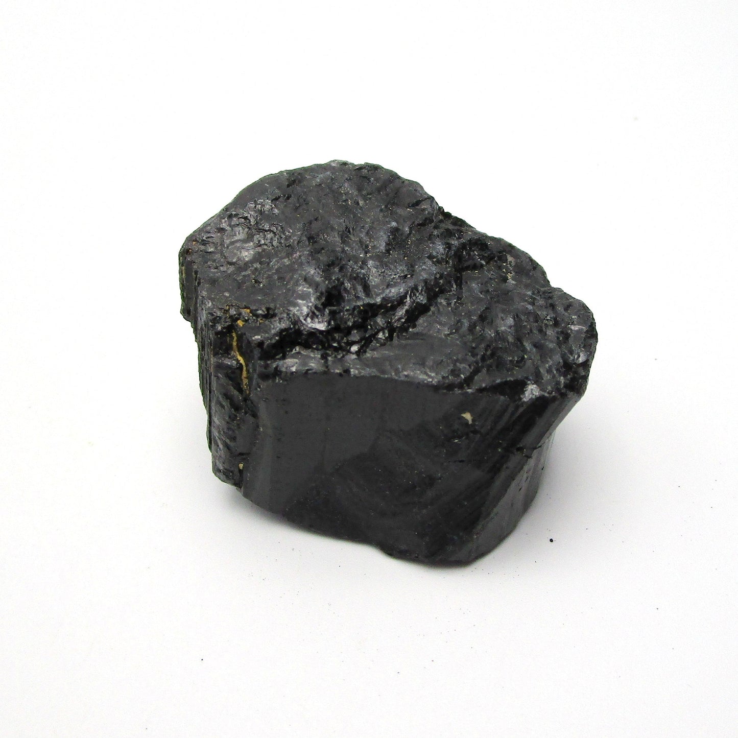 A rough, black tourmaline crystal with a metallic sheen, approximately 1 inch in size, displayed on a white background.