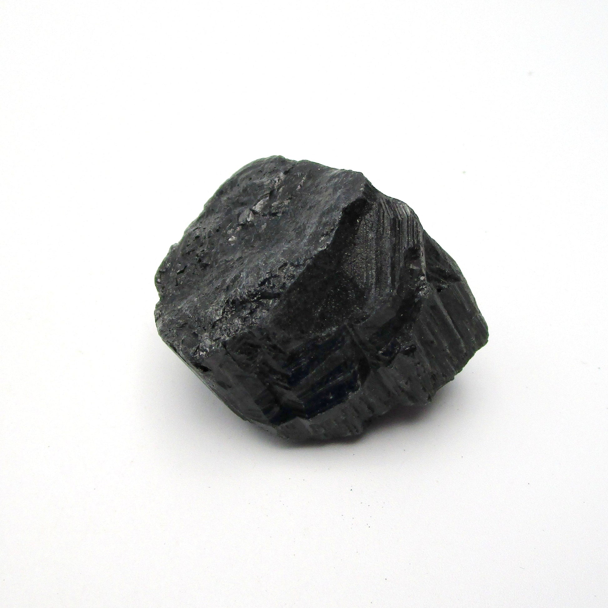 A rough, black tourmaline crystal with a metallic sheen, approximately 1 inch in size, displayed on a white background.