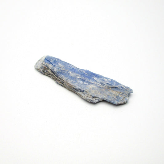 A rough, unpolished piece of blue kyanite crystal with natural imperfections on a white background