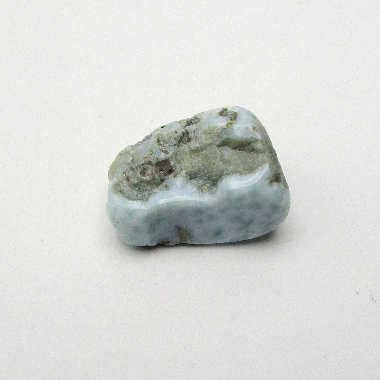 A polished, smoothed Larimar crystal with a blue and white color scheme, approximately 0.5 inches in size, placed on a white background.