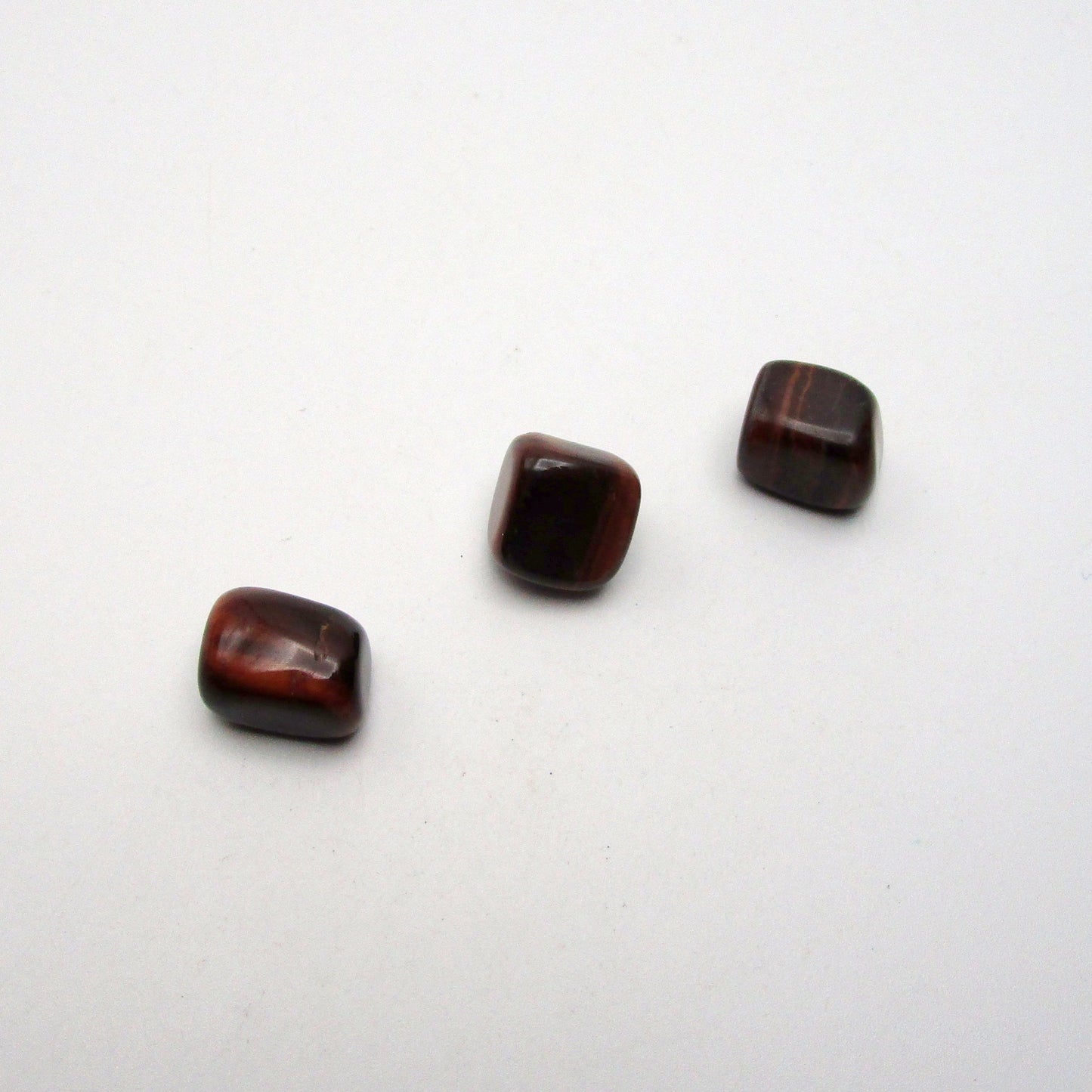 Set of three tumbled red tigers eye on white background